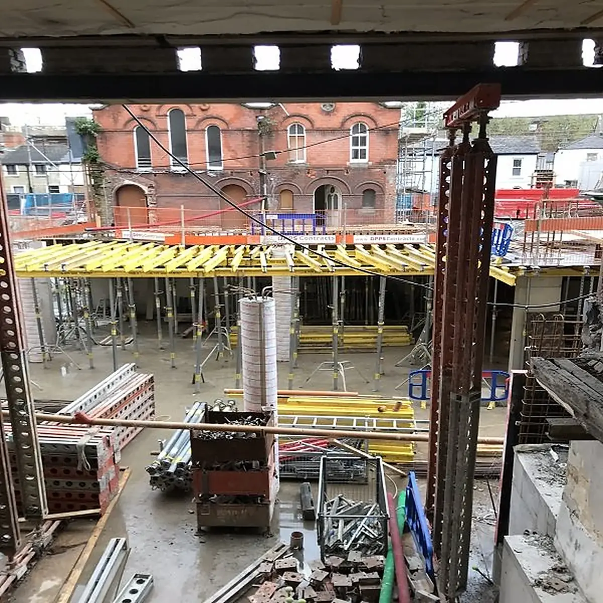 Active construction site with formwork, scaffolding and a heritage building behind
